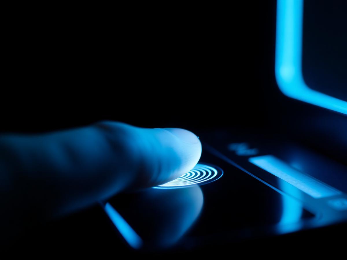 Finger on a biometric fingerprint scanner glowing blue